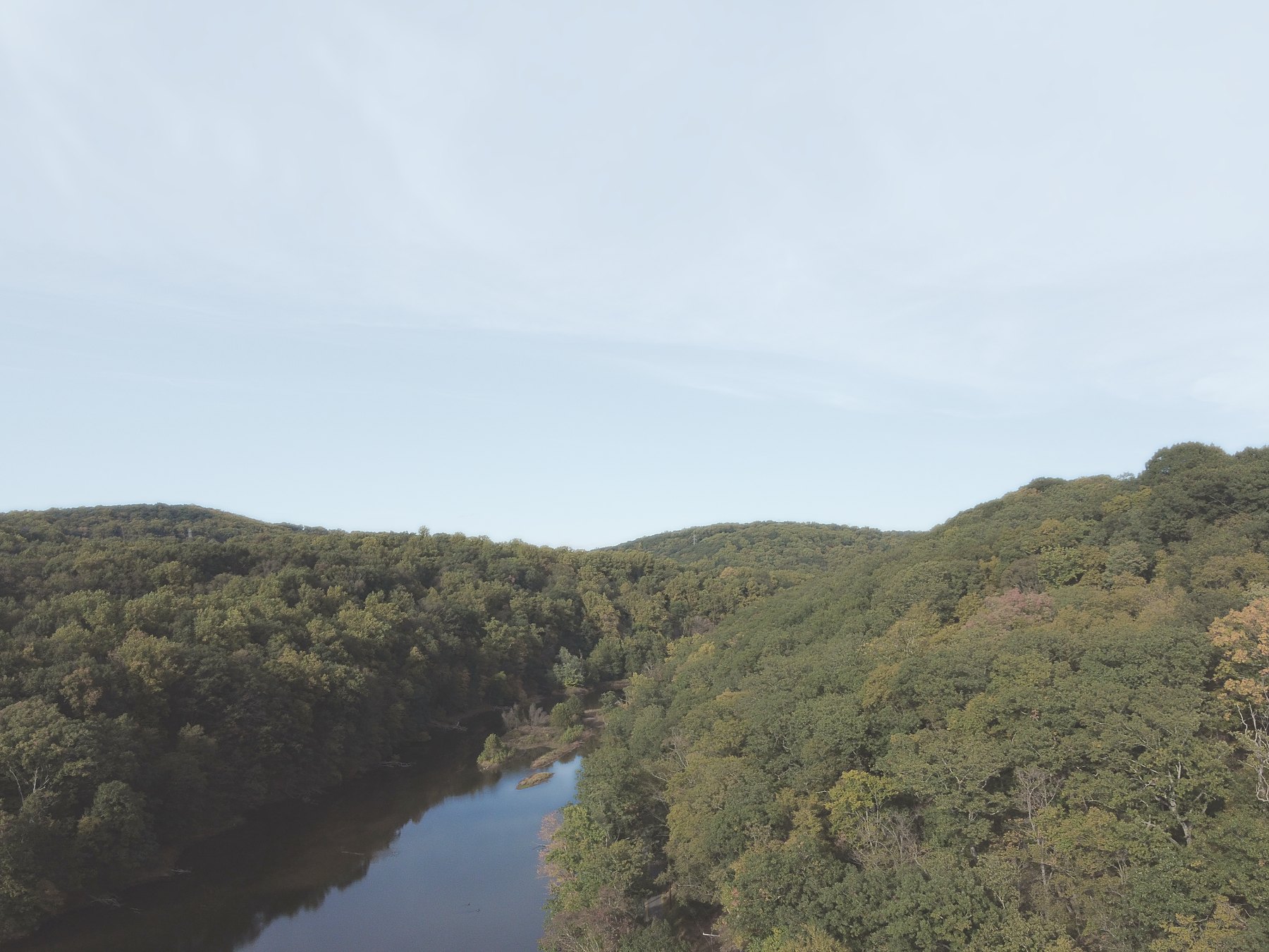 Looking down into a wooded river valley, the river winding between the hills
